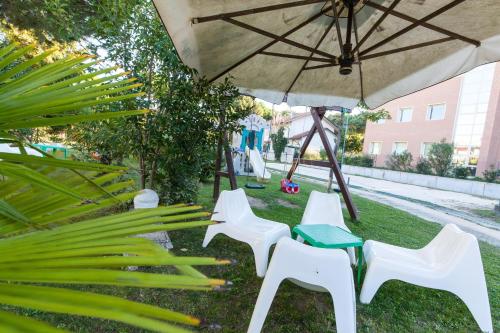 a group of white chairs and an umbrella at Villa Liliana in Cervia