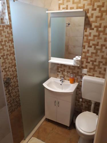 a bathroom with a toilet and a sink and a mirror at Vila & Apartments MATEA in Gevgelija