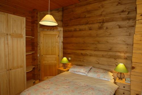 - une chambre avec des murs en bois et un lit avec deux lampes dans l'établissement Chamonix Chalets, aux Houches