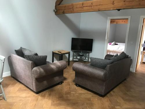 a living room with two chairs and a television at Rolling Mill, Wolds Way Holiday Cottages, 2 Bed, 1st floor in Cottingham
