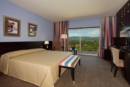um quarto de hotel com uma cama e uma grande janela em Hotel Casino Chaves em Chaves
