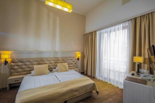 a bedroom with a large bed and a large window at Session Hotel Ráckeve in Ráckeve