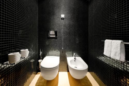 a black tiled bathroom with a toilet and a bidet at Hotel Casino Chaves in Chaves