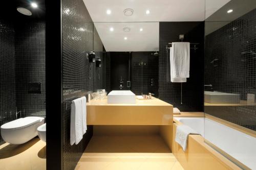 a bathroom with a sink and a tub and a toilet at Hotel Casino Chaves in Chaves