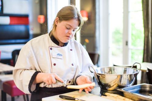 une femme dans une cuisine préparant de la nourriture sur un comptoir dans l'établissement Het Oude Kantongerecht, à Apeldoorn