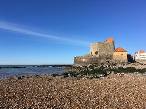 a castle on a rocky beach next to the water at FACE A LA MER , L ARTISTE in Ambleteuse