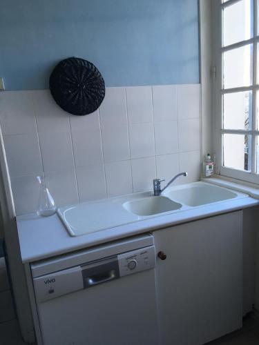 a white kitchen with a sink and a window at FACE A LA MER , L ARTISTE in Ambleteuse