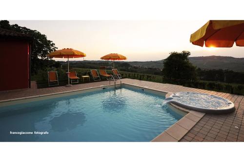 a large swimming pool with chairs and umbrellas at Agriturismo Bianconiglio in Monforte dʼAlba