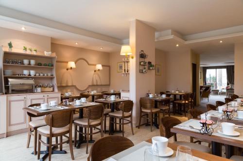 un restaurant avec des tables et des chaises dans une salle dans l'établissement Hotel Albert 1er, à Rueil-Malmaison