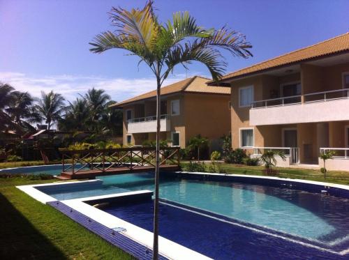 a palm tree in front of a house with a swimming pool at Residencial Verano in Guarajuba