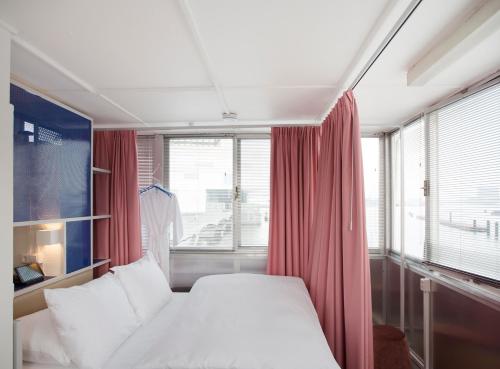 1 dormitorio con 1 cama y una ventana con cortinas rojas en SWEETS - Westerdoksbrug, en Ámsterdam