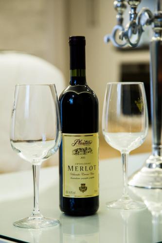 a bottle of wine sitting next to two wine glasses at Apartment Exclusive and Studio in Subotica