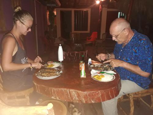 a man and a woman sitting at a table eating food at Hospedaje Bananas in Altagracia