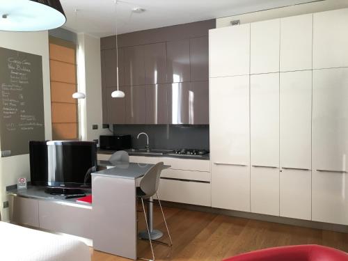 a kitchen with white cabinets and a desk with a computer at Corso Como New Building Apartment in Milan