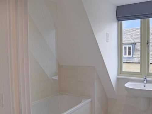 a bathroom with a sink and a bath tub next to a window at Hawthorn in Cheltenham