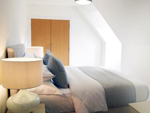 a bedroom with a bed with blue pillows and a lamp at Hawthorn in Cheltenham
