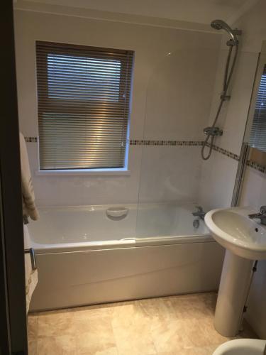 a bathroom with a tub and a sink and a window at Millie,s View 18 hole free Golf in Swarland