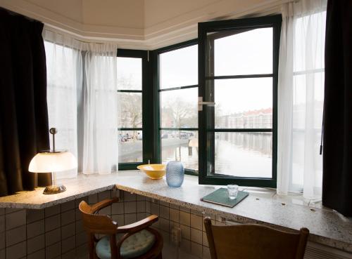 eine Küche mit Fenstern und einem Tisch mit einem Stuhl in der Unterkunft SWEETS - Kattenslootbrug in Amsterdam