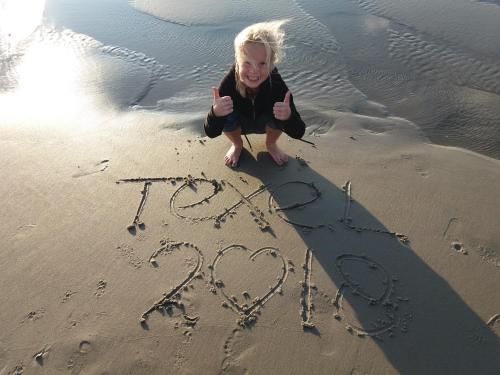 a little girl writing in the sand on the beach at Vakantiepark Dennenoord in Den Burg
