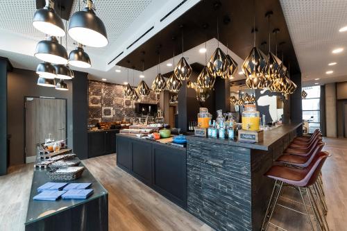 a restaurant with a bar with brown leather chairs at HARBR. hotel Heilbronn in Heilbronn