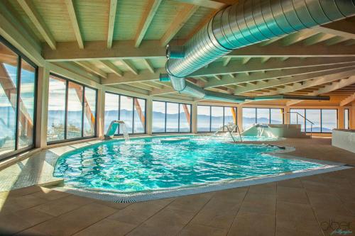 a large swimming pool in a building with windows at The Rock Suites & Spa in Congosto