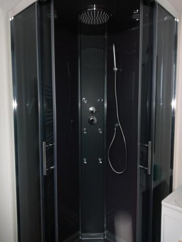 une douche avec une porte vitrée dans une salle de bain dans l'établissement Le Valentin, à Eaux-Bonnes