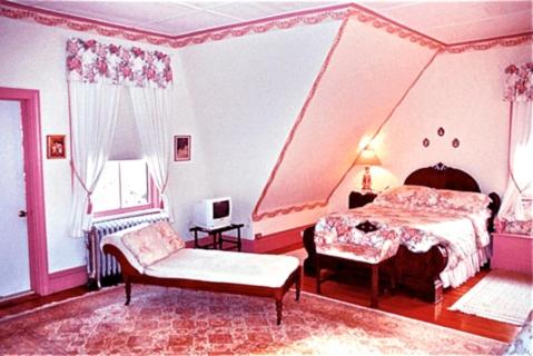 a pink bedroom with a bed and a chair at Whistler's Inn in Lenox