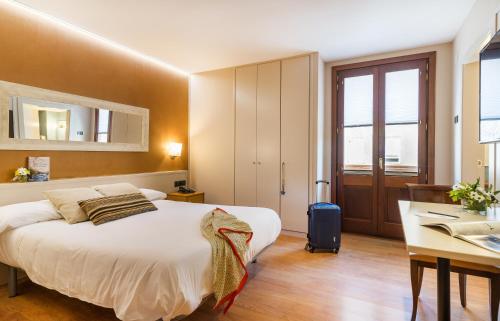 Habitación de hotel con cama, escritorio y escritorio. en Hotel Els Caçadors de Ribes, en Ribes de Freser
