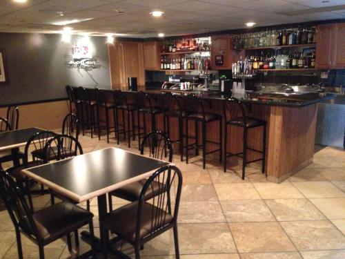 a bar with black tables and chairs in a restaurant at AmericInn by Wyndham Aberdeen Event Center in Aberdeen