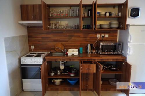 a kitchen with wooden cabinets and a stove at Chata Zemplin in Kaluža