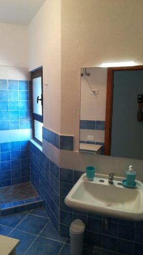 a blue tiled bathroom with a sink and a mirror at CASE BELVEDERE in Chia