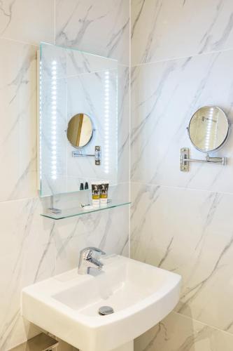 a white bathroom with a sink and mirror at Mercure Newbury West Grange Hotel in Thatcham