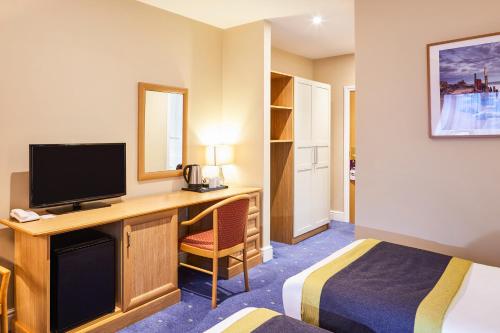 a hotel room with a desk with a television at Mercure Newbury West Grange Hotel in Thatcham
