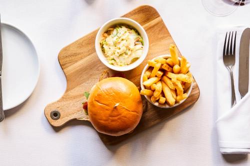 a sandwich and a bowl of coleslaw and fries on a cutting board at Mercure Newbury West Grange Hotel in Thatcham