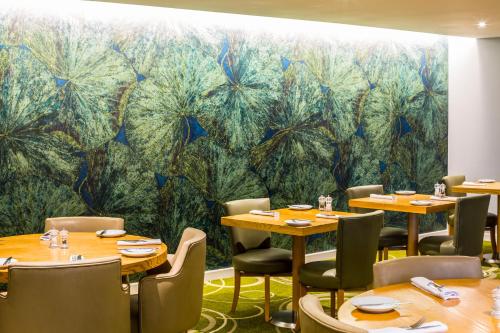 a restaurant with tables and chairs and a mural at Mercure Newbury West Grange Hotel in Thatcham