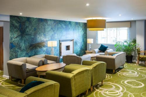 a waiting room with couches and tables and a mural at Mercure Newbury West Grange Hotel in Thatcham