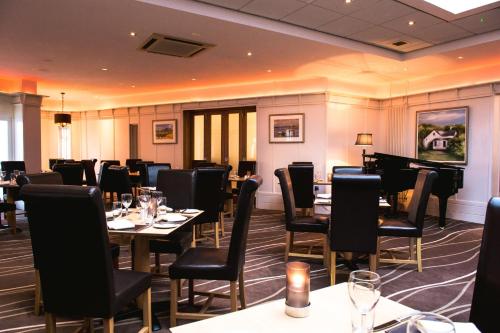a restaurant with tables and chairs and a piano at La Mon Hotel & Country Club in Castlereagh