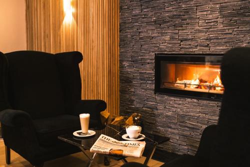 a living room with a fireplace and a chair and a table at La Mon Hotel & Country Club in Castlereagh