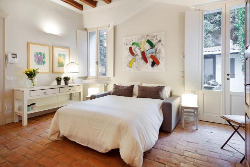 een slaapkamer met een groot wit bed en ramen bij La dimora medievale del Duca in Ferrara