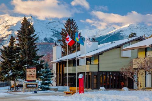 a ski lodge with snow covered mountains in the background at Jasper Inn & Suites by INNhotels in Jasper