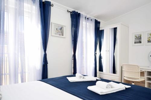 a bedroom with blue curtains and a bed with two towels at Santana 4 - Checkinhome in Lisbon