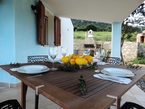 una mesa de madera con platos y copas de vino. en la casetta rosa, en Tertenìa