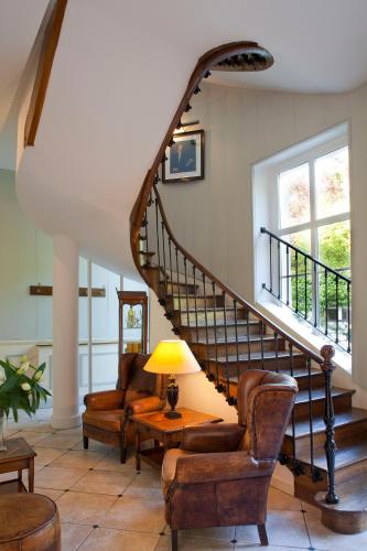 a staircase in a living room with chairs and a lamp at Domaine et Golf de Vaugouard - La Maison Younan in Fontenay-sur-Loing