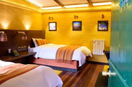 a bedroom with two beds and a yellow wall at Hotel Jardines de Uyuni in Uyuni