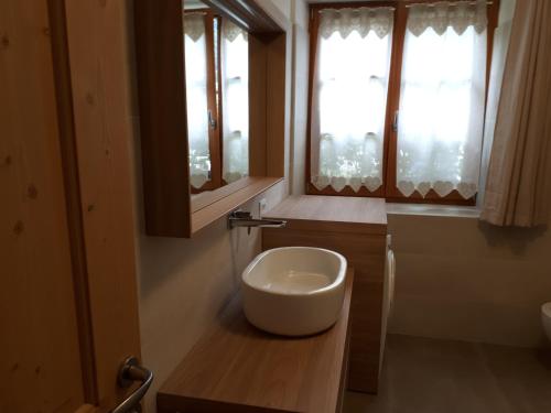 un bagno con lavandino bianco e due finestre di Casa Cristina 1 a Molveno