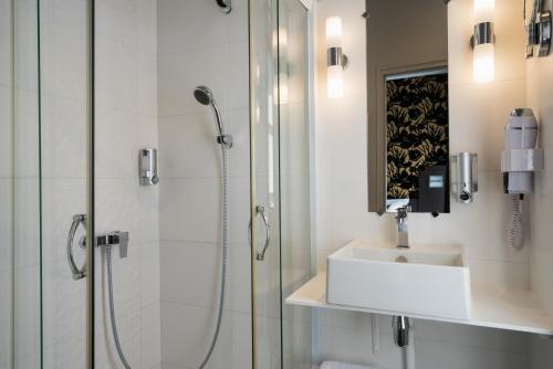 a bathroom with a glass shower and a sink at Hotel Voltaire Opera Nantes Centre in Nantes