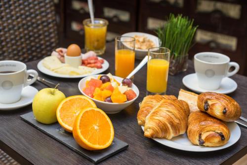a table with a breakfast of croissants fruit and juice at Hotel Voltaire Opera Nantes Centre in Nantes