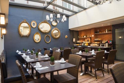 un restaurante con mesas, sillas y espejos en la pared en Hotel Voltaire Opera Nantes Centre, en Nantes