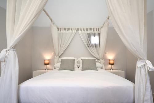 セビリアにあるPalacio Buenavistaの白いベッドルーム(カーテン付きの白いベッド付)