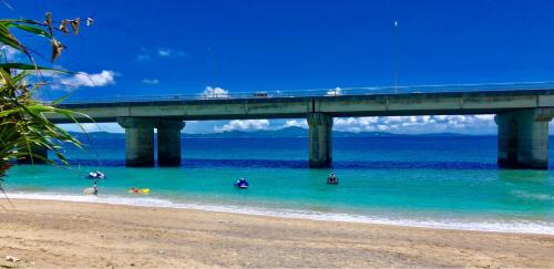 a bridge over a beach with people in the water at Oceans Cottage in Nago